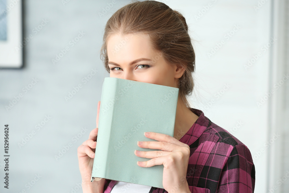 Beautiful young woman with book at home