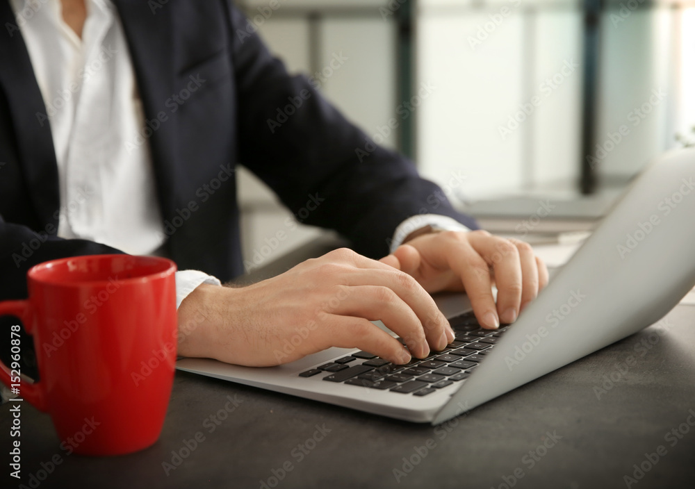 Young businessman working with laptop in office, closeup
