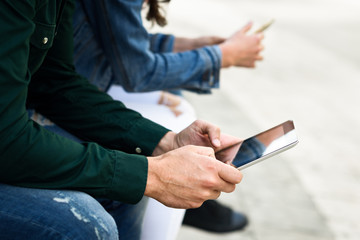 Wall Mural - Young unrecognizable people using smartphone and tablet computers outdoors