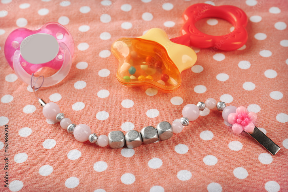 Pacifier clip with place for baby name, dummy and rattle toy on table