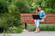 © dmshpak - Young attractive business woman with coffee and laptop in the park.