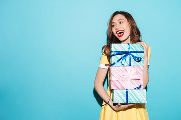 Wall Mural - Portrait of a pretty girl holding stack of gift boxes