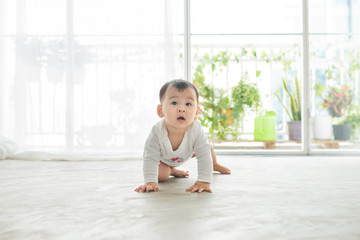 Little pretty baby girl crawling on the floor at home