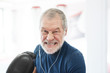 © Westend61 - Portrait of aggressive senior man with earphones and boxing gloves in gym