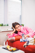 © Myroslava - Young sick sad woman lies on bed at home and keeps control desk in hand