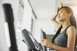 © eggeeggjiew - Asian woman with sweat exercising on Elliptical trainer machine at the gym.