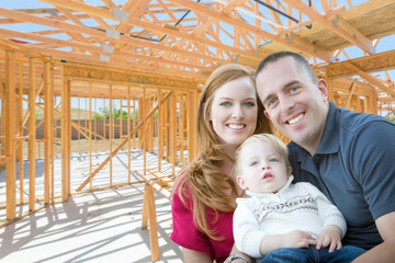 Young Military Family Inside The Framing of Their New Home at Construction Site.