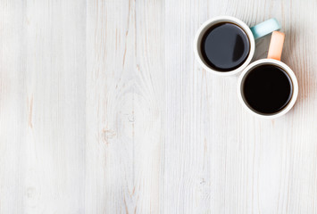 Two cups of coffee on white wooden table. Top view, flat lay.