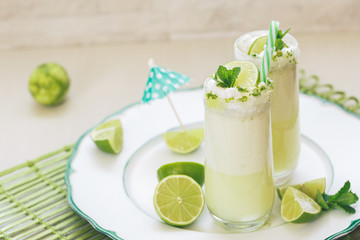 Refreshing  Brazilian lemonade or limeade in two sugar rimmed glasses,  decorated with lime slices and mint . Macro, selective focus, blank space