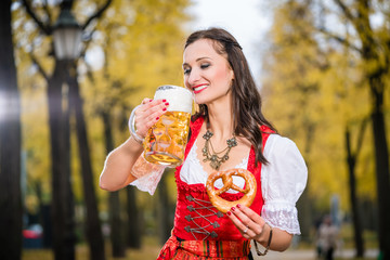 Wall Mural - Frau im traditionellen Dirndl, die Bierkrug und Brezel hält 