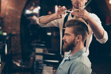 Profile View Of A Red Bearded Stylish Barber Shop Client. He Is Getting His Perfect Trendy Haircut From A Classy Stylist, Looking In A Mirror And Waiting For Result