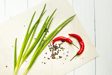 Wall Mural - Red chili pepper and green onion with spices on a white wooden background, top view.