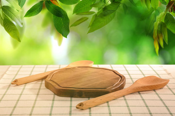 Wall Mural - Wooden board and other kitchen utensils on table in garden