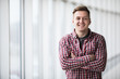 © dianagrytsku - Portrait of smiling man standing with hands crossed in modern building