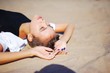 © raisondtre - Young pretty girl in black dress is lying on the sand with closed eyes under the bright rays of the sun, closeup