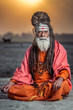 Portrait of sadhu sitting with sunrise behind him, Varanasi, India.
