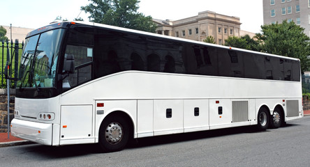 parked white tour charter bus with dark tinted windows.