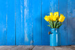 © eight8 - Bouquet of yellow tulips in vase on a blue background
