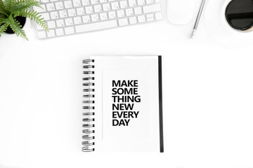 top view of make something new every day motivational quote in diary, computer mouse and keyboard isolated on white