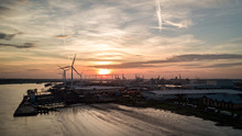 Dusk At The Port Of Tilbury, Essex, UK. Sunset View Of The Low Tide Of The River Thames And Wind Turbines Turning In The Background.