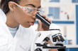 © LIGHTFIELD STUDIOS - concentrated african american scientist in lab coat working with microscope in chemical lab