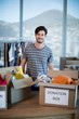 © WavebreakMediaMicro - Smiling man standing with donation box in office