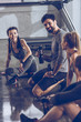 © LIGHTFIELD STUDIOS - group of athletic young people in sportswear sitting on floor and resting at the gym, group fitness concept