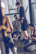 © LIGHTFIELD STUDIOS - group of athletic young people in sportswear sitting on floor and resting at the gym, group fitness concept