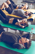 © LIGHTFIELD STUDIOS - Sporty young people doing abs on yoga mats while exercising at the gym