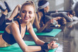 © LIGHTFIELD STUDIOS - Smiling young sportswoman lying on yoga mat and looking away while exercising at the gym