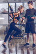 © LIGHTFIELD STUDIOS - side view of man helping sportive woman exercising with trx gym equipment