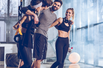 Wall Mural - side view of group of sportive people near trx equipment in gym