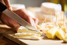 Staff Cutting Cheese At Counter In Market