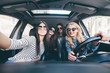 © F8  \ Suport Ukraine - Group of girls having fun in the car and taking selfies with camera on road trip