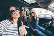 © F8  \ Suport Ukraine - Group of girls having fun in the car and taking selfies with camera on road trip