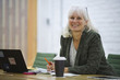 © Cavan Images - Portrait of smiling businesswoman with laptop computer sitting in board room at office