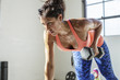 © Cavan Images - Female athlete lifting dumbbell while doing push ups in gym