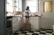 © Cavan Images - Rear view of girl washing dish in kitchen at home