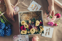 Overhead View Of Florist Arranging Flowers In Box On Table At Flower Shop