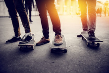 Boys Skateboarders Feet In Pants And Bryaks In Frayed Sneakers Stand On The Skateboard. Concept Of A Team Of Friends Doing Sports On The Asphalt Skateboarding