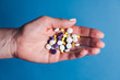 © SokRom - Hand holding pills on blue background