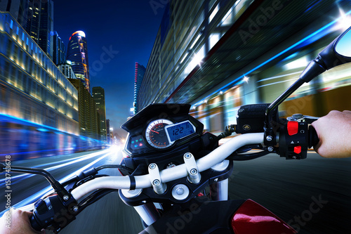 Biker driving a motorcycle rides along the city street , night scene Slika na platnu