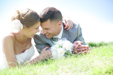 Cheerful bride and groom relaxing in grass