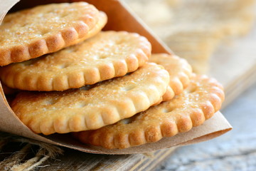 Dry salty cracker cookies in a wrapping paper. Crunchy savory crackers snack idea for kids or adults. Rustic stile. Closeup