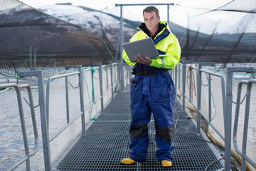 Worker using laptop at salmon farm