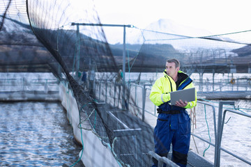 Worker using laptop at salmon farm