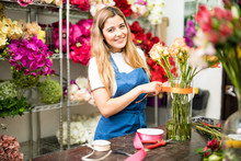 Young Florist Putting A Ribbon On A Glass Vase