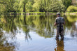 © murmakova - The fisherman walks in the river and flies on the Otava River. View from the rear of the fisherman.