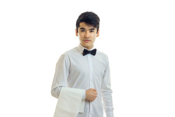 Wall Mural - beautiful strong young waiter in a white shirt with a butterfly looks straight and keeps towel on hand