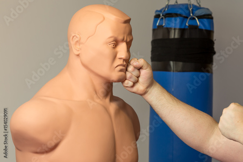 Caucasian fighter with bare hands punching straight on a dummy mannequin doll on Canvas Print